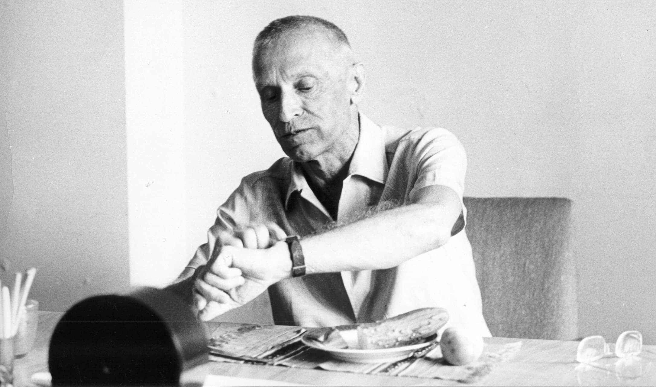 Mykola Amosov checking his watch at a table