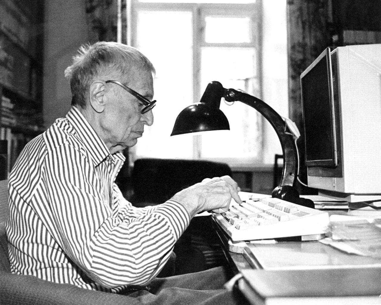 Mykola Amosov at his desk, writing at the computer